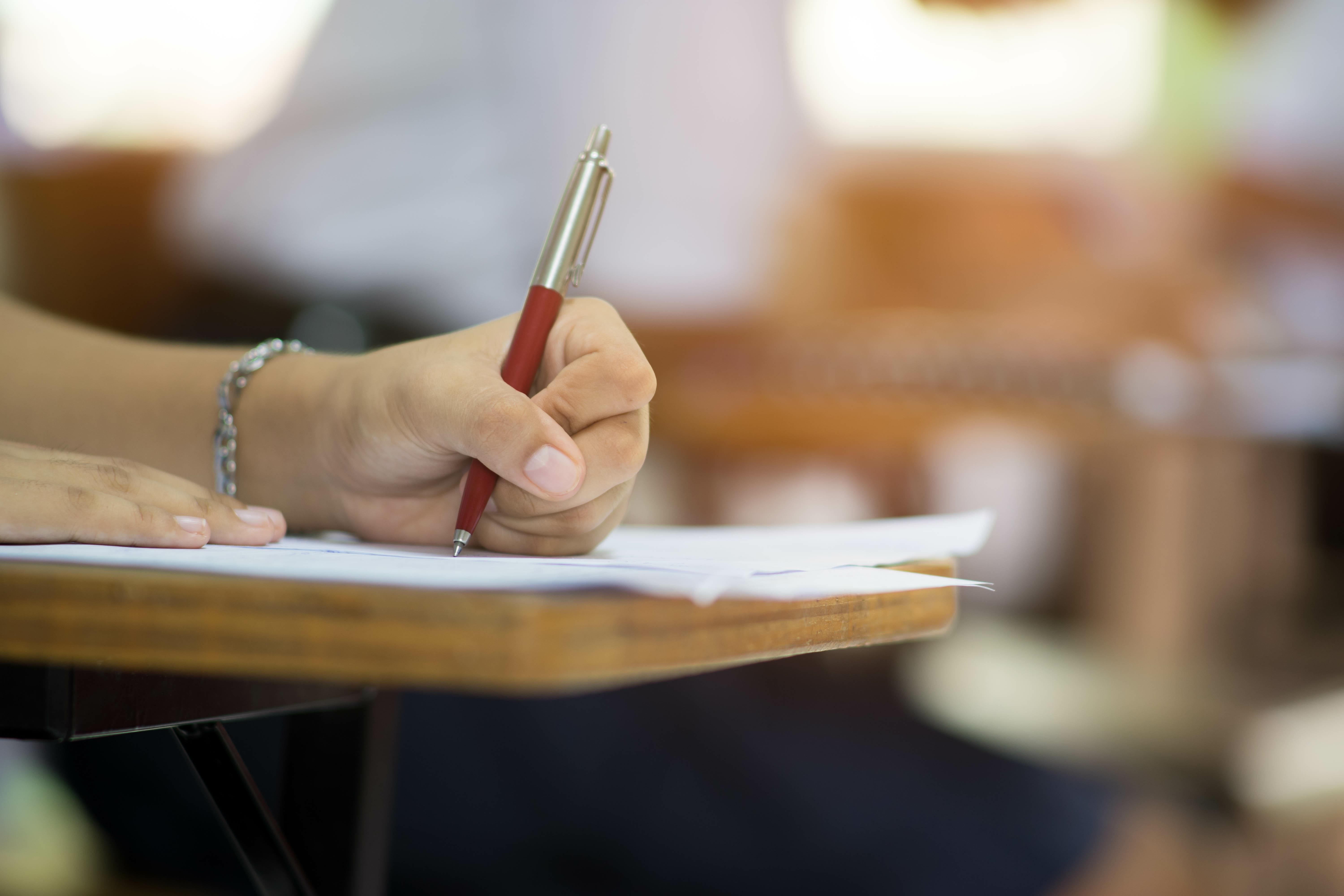 关闭up to hand of student holding pen and taking exam in cl